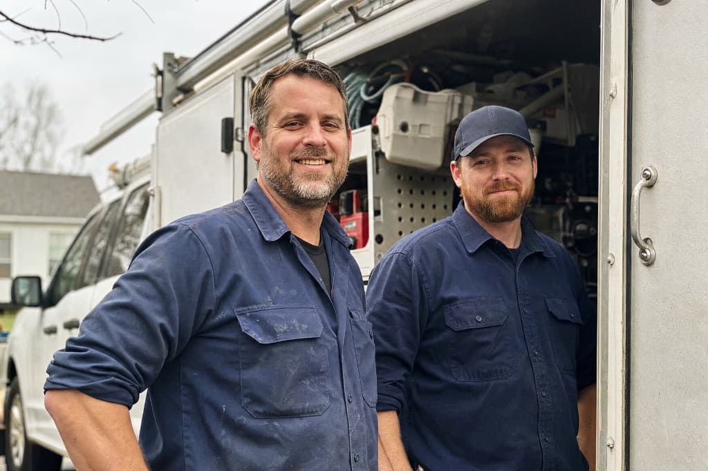 Summit Pipe & Drain plumbers standing in front of their service van